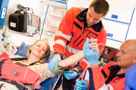 Paramedics measuring blood pressure to patient ambulance feeling in pain