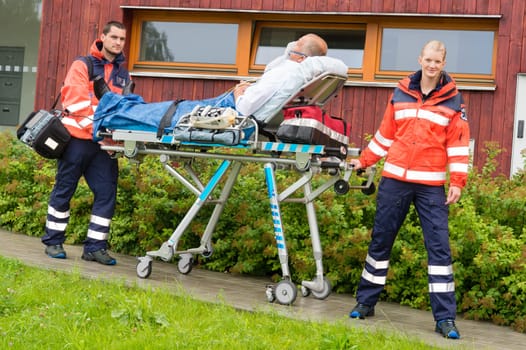 Paramedics with patient on emergency stretcher ambulance aid woman man