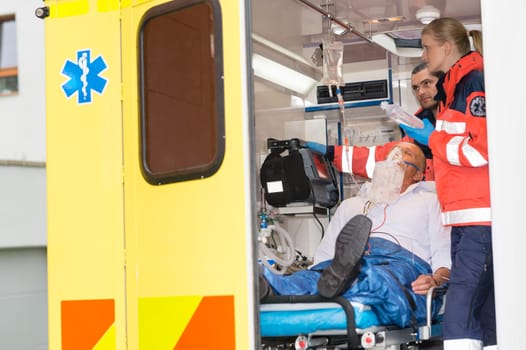Paramedics checking IV drip patient in ambulance treatment aid emergency