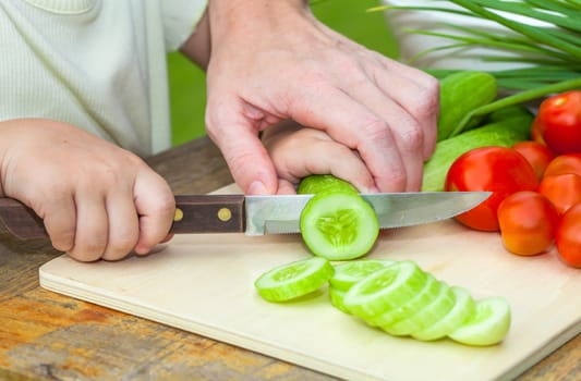sliced cucumber. Mother teaches daughter  knife cut cucumber