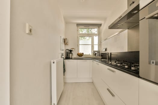 a long narrow kitchen with white cabinets and black counter tops on the walls, along with an open door that leads to another room