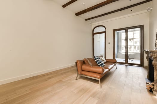 a living room with wood flooring and exposed beams on the ceiling above it is a brown leather chair in front of a fireplace