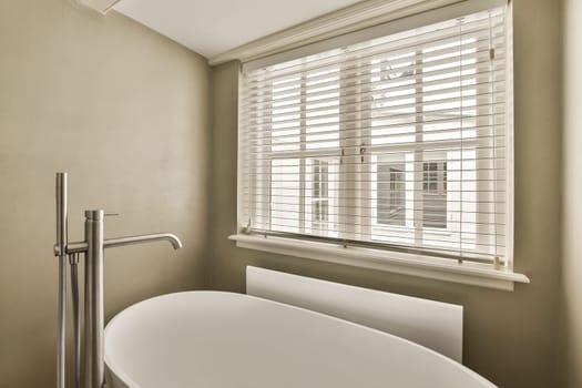 a bathtub in the corner of a bathroom with shutters on the window behind it is an outside view