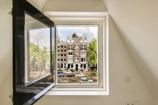 a city seen through a window in a room with white walls and black trim on the windows, there is a view of buildings