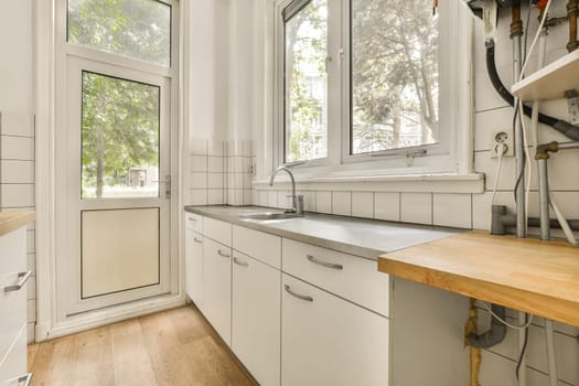 a kitchen with white cabinets and wood counter tops in front of a window that looks out to the trees outside