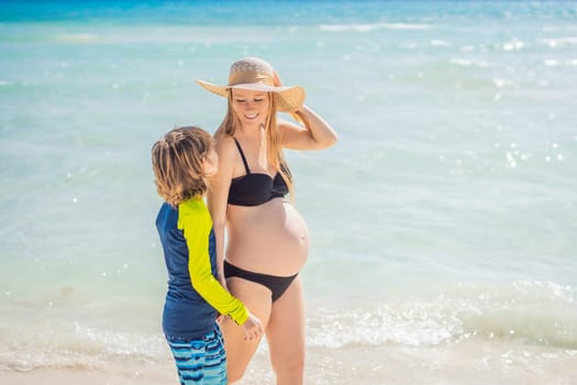 A radiant pregnant mother and her excited son share a tender moment on a serene, snow-white beach, celebrating family love amidst nature's beauty.