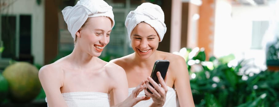 Couple of young beautiful women with beautiful skin in white towel taking a photo together at outdoor surrounded by peaceful natural environment. Beauty and healthy spa concept. Tranquility.