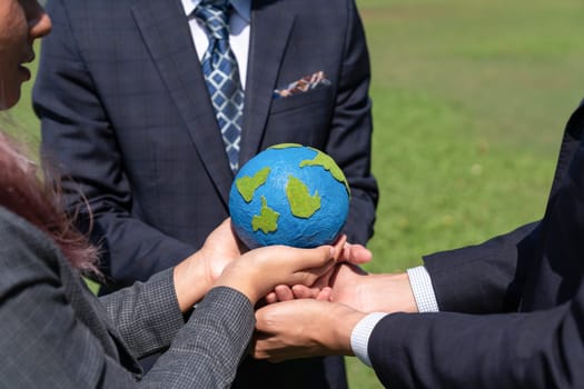 Group of business people hold planet Earth globe together as Earth day concept. Mission to save Earth by business commitment to environment friendly methods and sustainable practices. Gyre