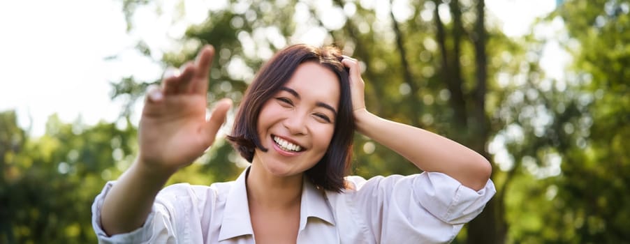 People and emotions concept. Happy asian woman laughing and smiling, posing on summer day in park. Copy space