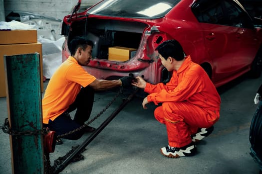 Mechanic testing strength and reliability of chain hoist for car towing in car workshop garage. Automotive service worker ensure through inspection of mechanical equipment. Oxus