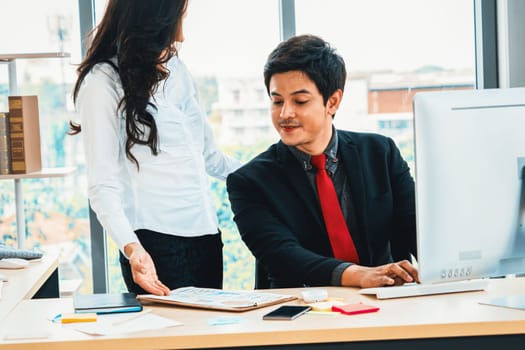 Two business people talk project strategy at office meeting room. Businessman discuss project planning with colleague at modern workplace while having conversation and advice on financial report. Jivy