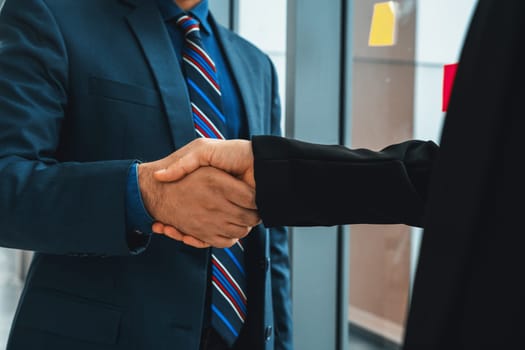 Business people handshake in corporate office showing professional agreement on a financial deal contract. Jivy