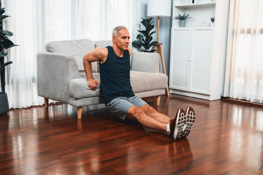 Athletic and active senior man using furniture for effective targeting muscle with push up at home exercise as concept of healthy fit body lifestyle after retirement. Clout