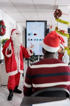 Motivational speaker dressed as Santa Claus inspiring workers to advance their careers in festive adorn office. Coworking meeting attendees learning corporate skills during xmas holiday season