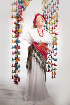 Portrait of cheerful funny adult mature woman solokha. Female model in clothes of national ethnic Slavic style. A stylized Ukrainian, Belarusian or Russian woman poses in a comic photo shoot