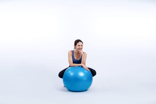 Young attractive asian woman portrait in sportswear with fit ball targeting on abs muscle for effective energetic daily workout routine. Studio shot and isolated background. Vigorous