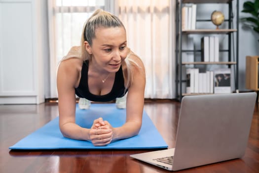 Athletic and sporty senior woman planking on fitness exercising mat while watching online fitness video at home exercise as concept of healthy fit body lifestyle after retirement. Clout