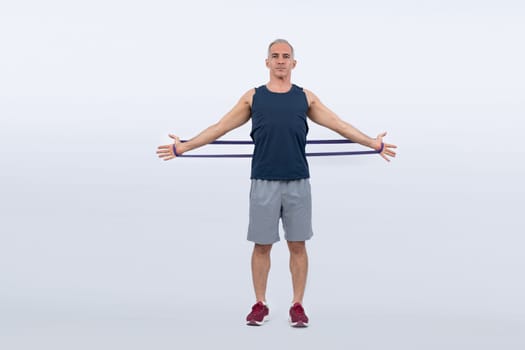 Full body length shot athletic and sporty senior man with fitness resistance band on isolated background. Healthy active physique and body care lifestyle after retirement. Clout