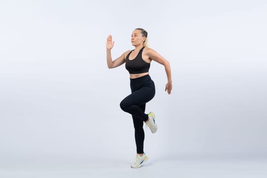 Active and fit physique senior woman in sportswear portrait in running posture isolated background. Healthy lifelong senior people with fitness healthy and sporty body care lifestyle concept. Clout