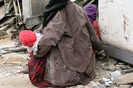 Mother and children near a destroyed house