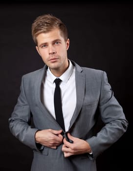Confident young businessman buttoning suit