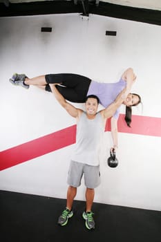 Handsome man lifting a beautiful woman at the gym