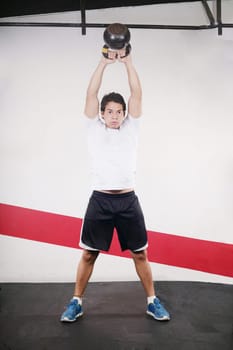 Young man doing kettlebell workout on gym