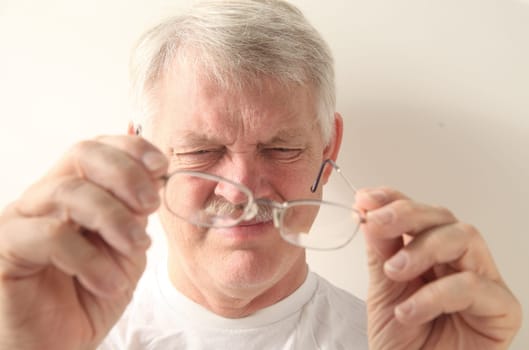 an older man squints at his glasses