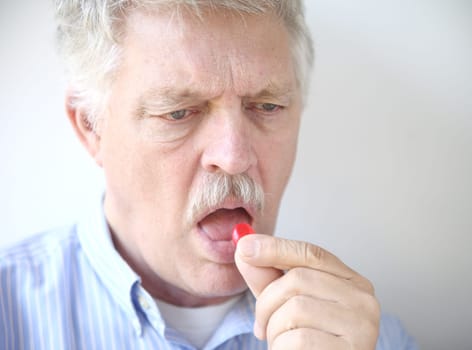 older man takes a throat lozenge for a sore throat