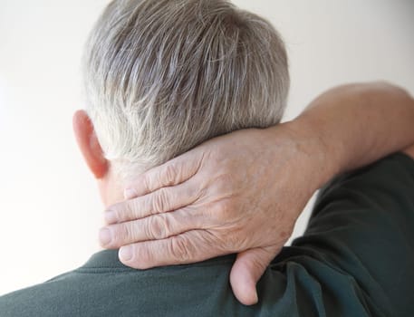 rear view of a man putting his hand on his aching neck