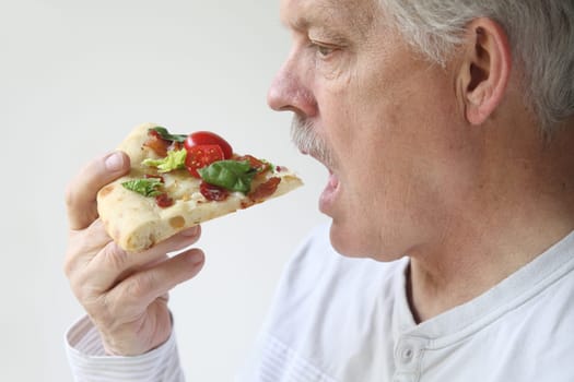 man eats BLT pizza profile view