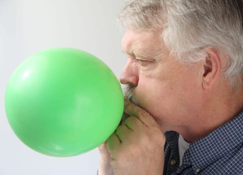 a man blows up a green balloon