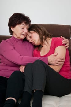 Mother senior woman) comforts her depressed aduld daughter at home