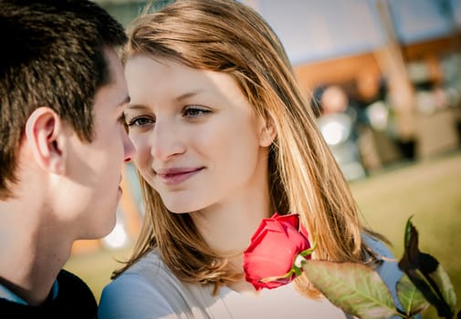 Intimate moment - young couple, woman holding red rose