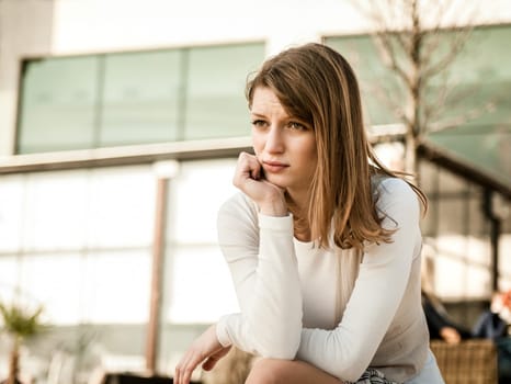 Depression - portrait of young worried woman oudoor in urban environment