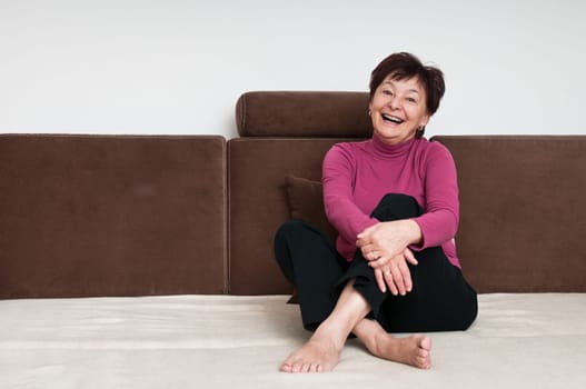 Portrait of smiling senior woman sitting on sofa at home