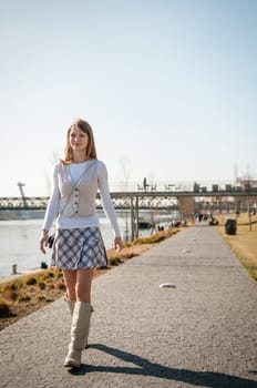 Beautiful young woman walking on the footpath - outdoor with blue sky