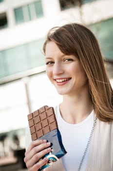 Portrait of young beautiful woman eating chocolate - lifestyle outdoor image