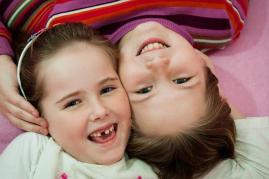 Portrait of smiling cute children (sisters) at home lying in bed