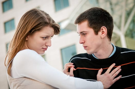 Lifestyle image of young woman refusing man outside on street having relationship problems
