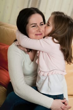 Child (cute ligirl) kissing her mother - indoors at home