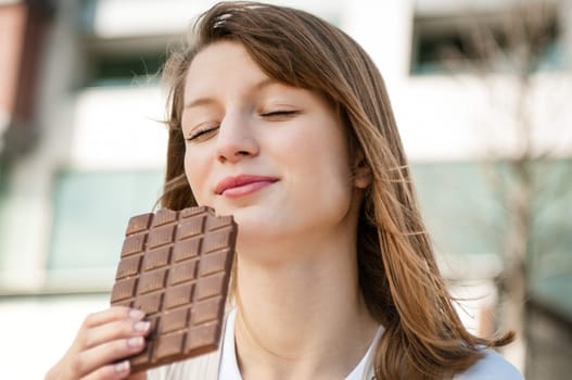 Portrait of young beautiful woman eating chocolate - lifestyle outdoor image