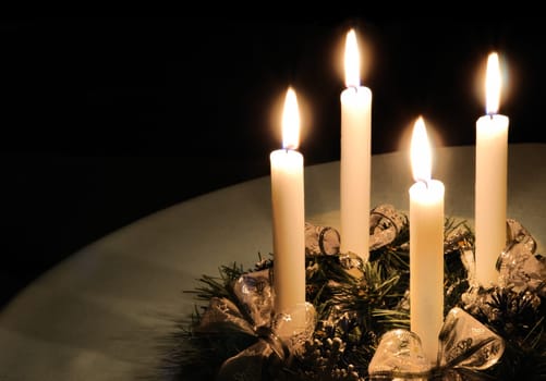 Christmas advent wreath with burning candles laid on table with black background