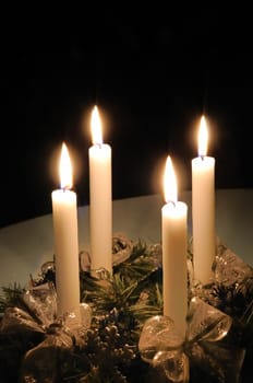 Christmas advent wreath with burning candles laid on table with black background