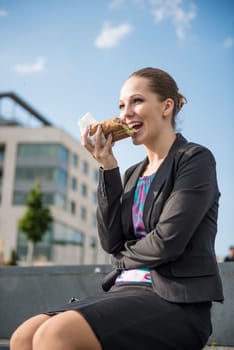 Smiling business woman eating outdoor - break from work for lunch