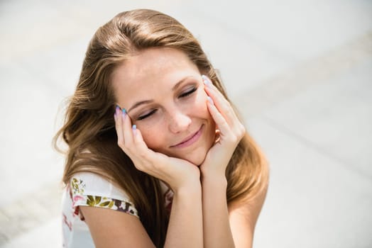 Outdoor portrait of young happy woman dreaming - hands under chin
