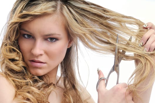 Young beautiful woman cutting her hair with scissors - very unhappy expression, isolated on white background