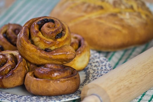 A plate of fresh Chelsea buns and a loaf of bread with shallow depth of field