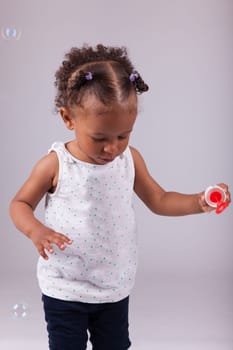 Cute little African American girl playing with soap bubbles