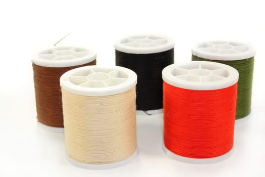 Different colored sewing thread against white background